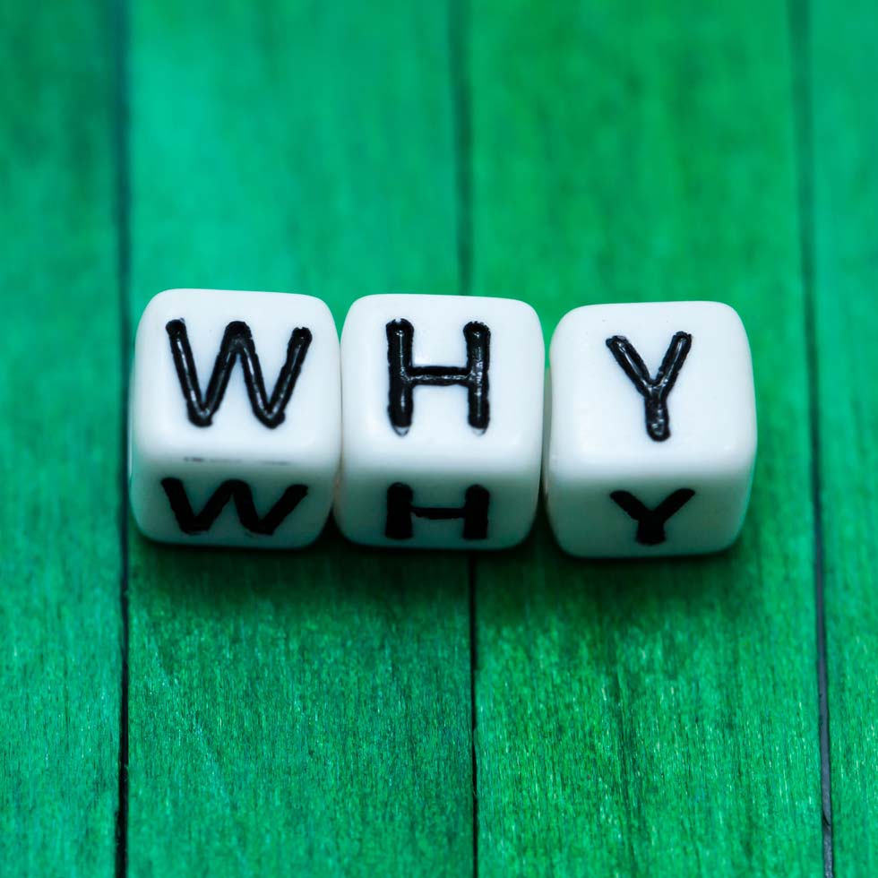 Three dice that spell out the word "WHY" on a green wooden table